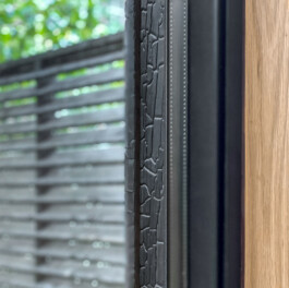 Detail where the interior oak library shelf meets the steel window frame against Shou Sugi Ban wood exterior.