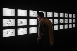 Visitor observing the geometric patterns of visitor interactions on a wall of iPads designed by IJarchitecture for a Random International digital art piece at NXT Museum.