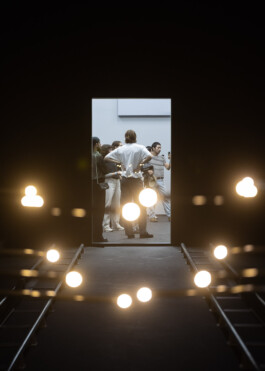 The view through the illuminated '15 Points' installation at NXT Museum, looking back towards the first exhibition space through a window.