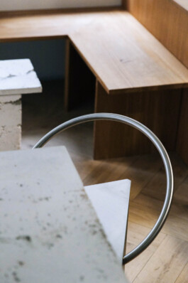 Detail of concrete table corner with Frama steel chair, concrete coffee table, and wooden bench in the background at Saint-Jean bakery, designed by IJarchitecture. 