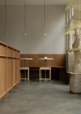 Interior of Saint-Jean Deli in Amsterdam by IJarchitecture, with oak counter, banquette seating, Frama Ovoid pendant lights, concrete floor and art display object. 