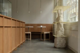 Saint-Jean Deli Amsterdam interior by IJarchitecture, featuring an oak counter, concrete floor, seating area, Frama Ovoid pendant lamps and an art display object by the window.