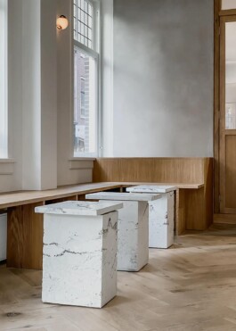 Bespoke oak bench and white white concrete tables in the interior of Saint-Jean Bakery in Amsterdam by IJarchitecture. 