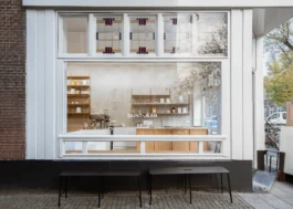 Exterior view of Saint-Jean Bakery in Amsterdam by IJarchitecture, showing the large front window and custom interior beyond. 