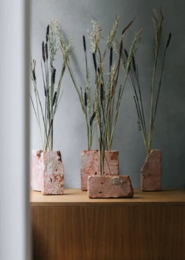 Interior styling detail at Saint-Jean Bakery in Amsterdam by IJarchitecture, with natural grasses in raw brick holders on an oak surface. 