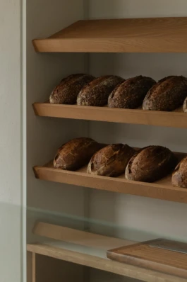 Bread niche with bespoke wooden shelves at Saint-Jean Deli in Amsterdam, designed by IJarchitecture.